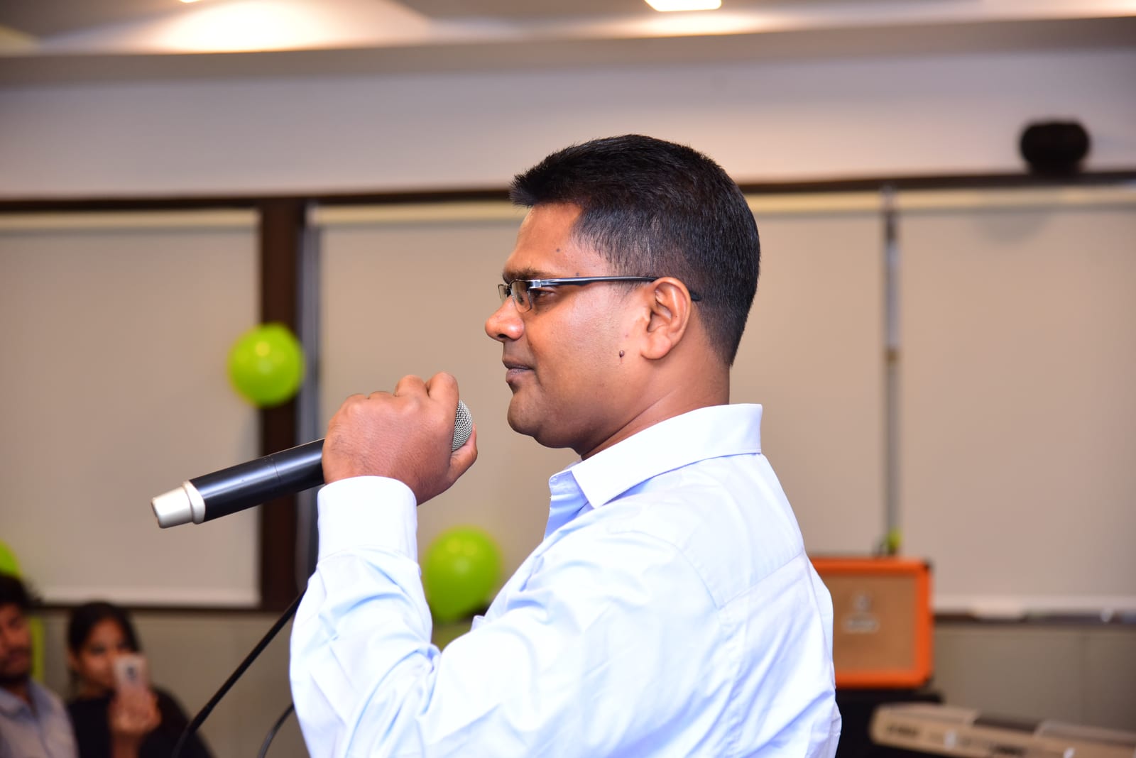 Saji Mathews speaking into a microphone, seen in profile