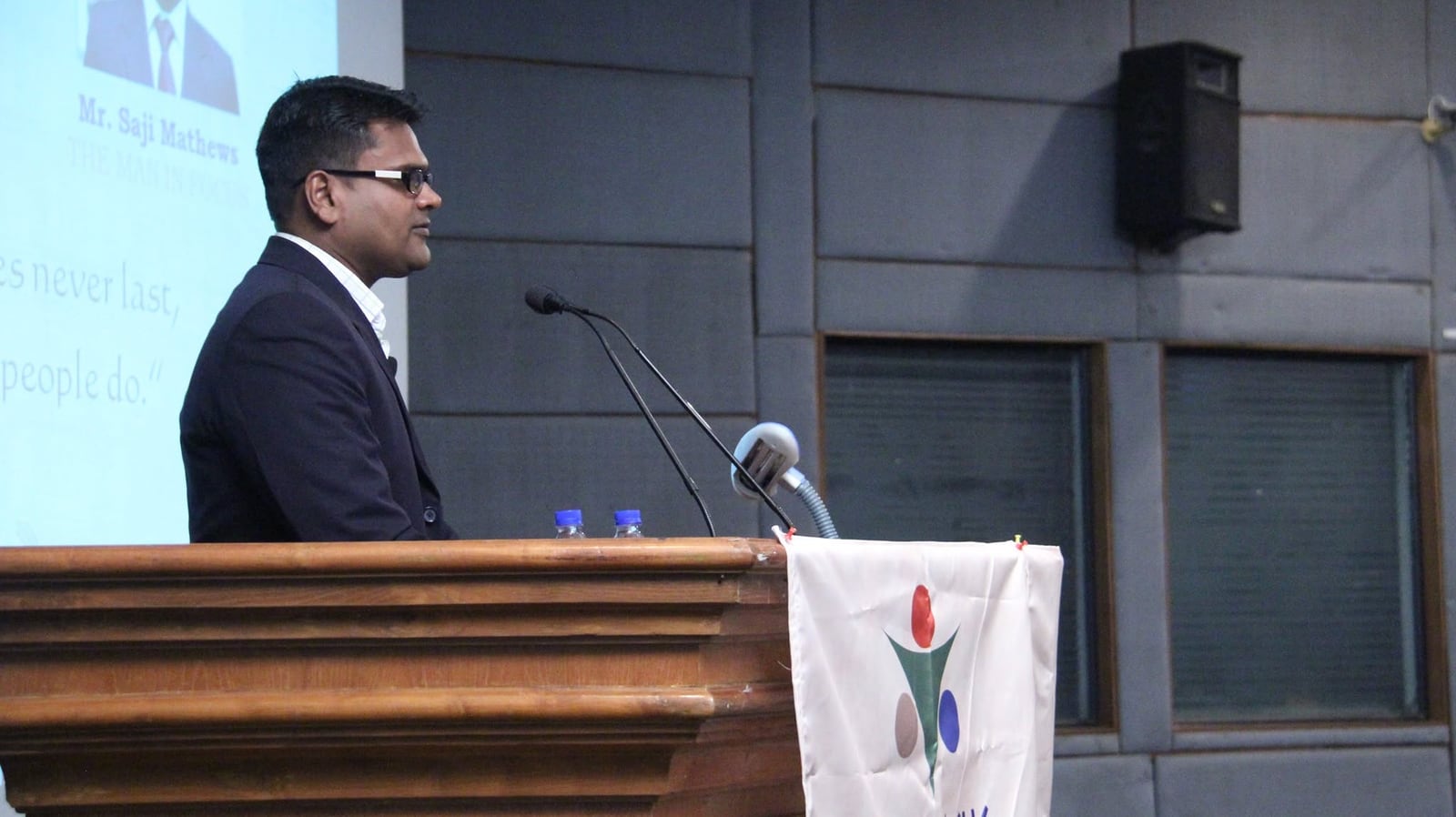 Saji Mathews at a lectern